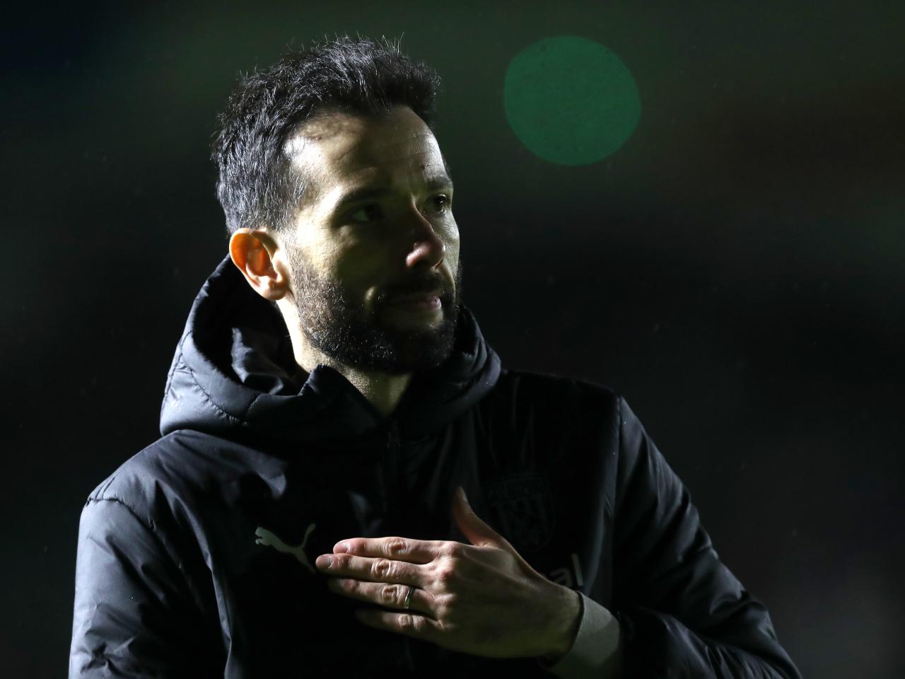 Carlos Corberan touches his heart as he looks at Albion fans in the away end at Plymouth