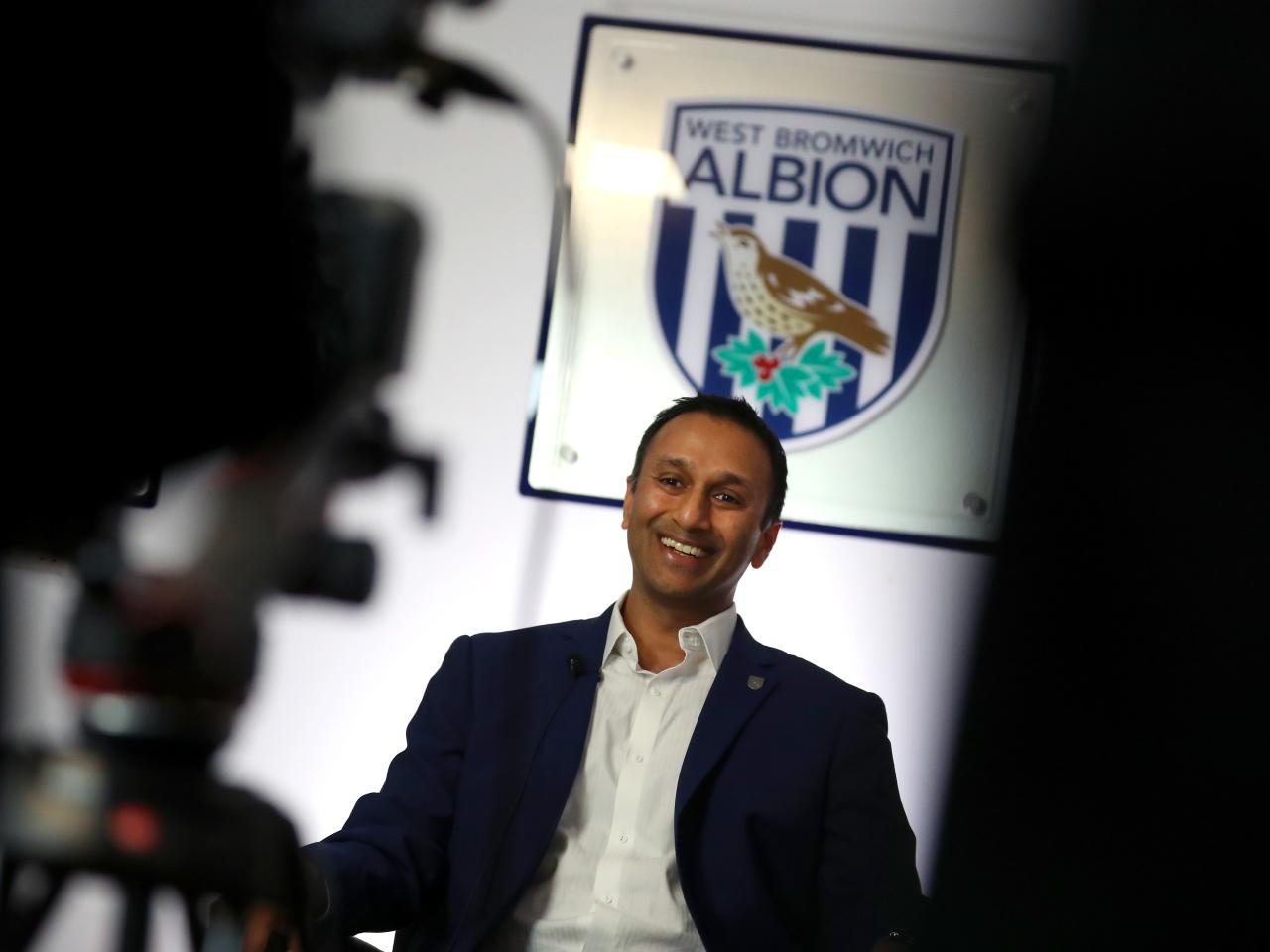Shilen Patel is interviewed in front of a big Albion badge 