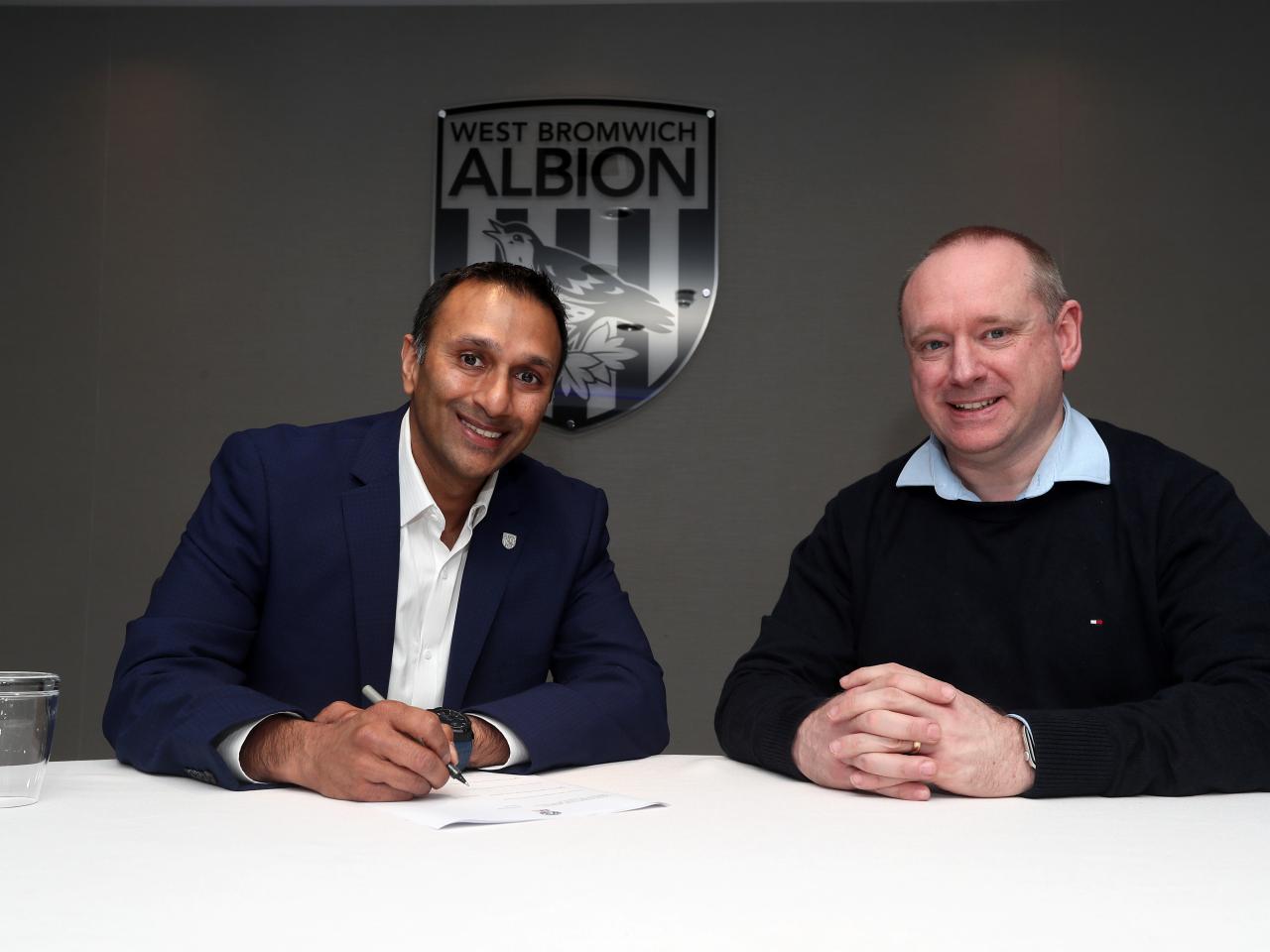 Shilen Patel sat at a table signing a contract with Mark Miles by his side