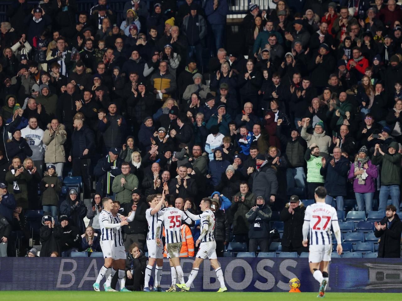 Albion players celebrate scoring against Cardiff with supporters in the stands behind them