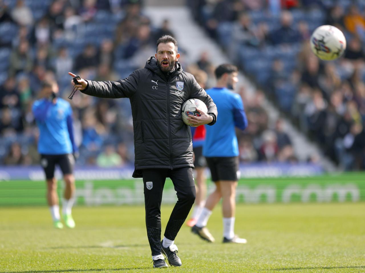 Carlos Corberán pointing while holding a football during a training session