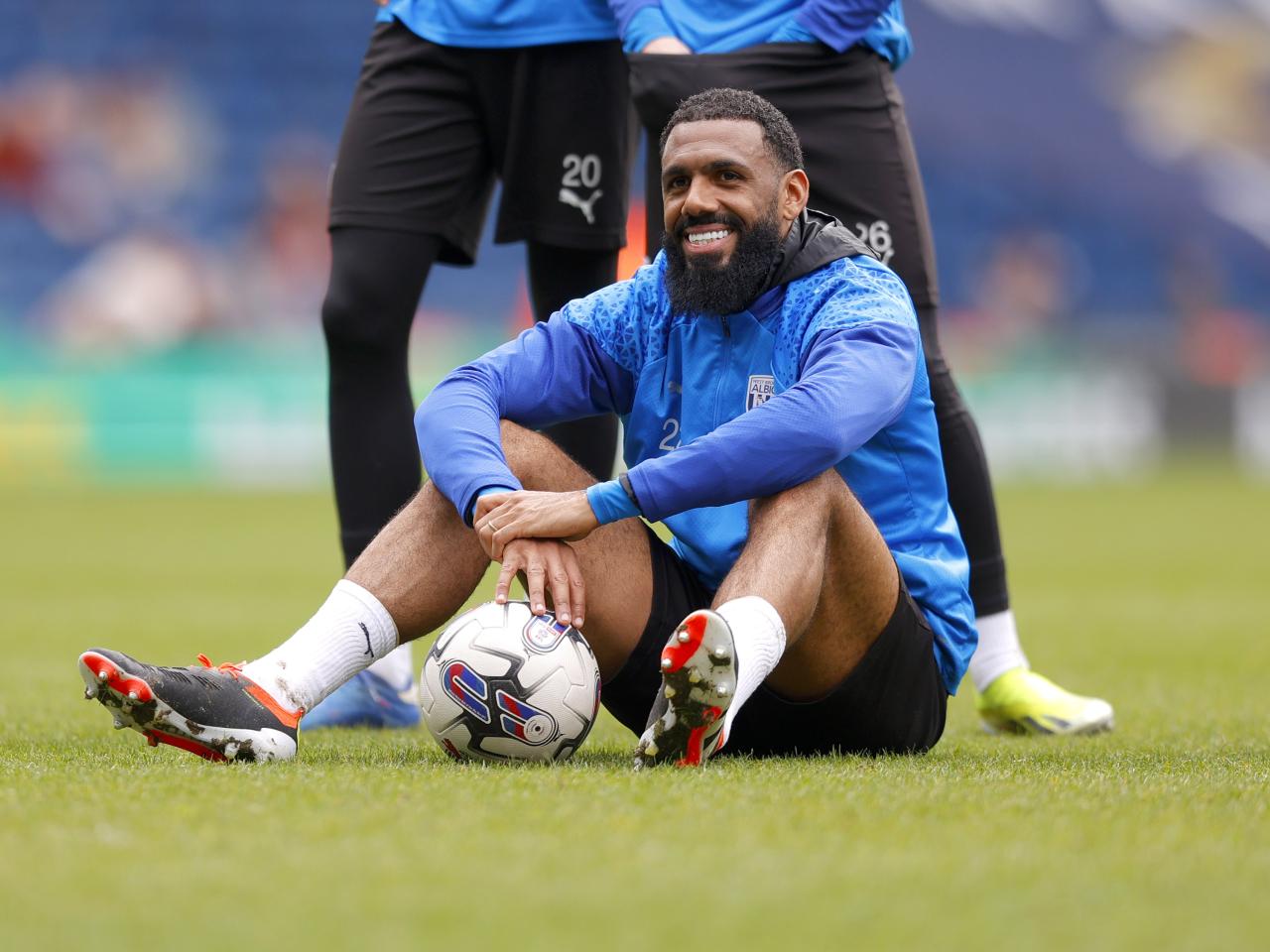 Yann M'Vila smiling while sat on the pitch at The Hawthorns