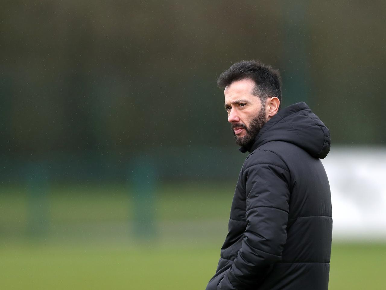 Carlos Corberán wearing a black coat while watching a training session