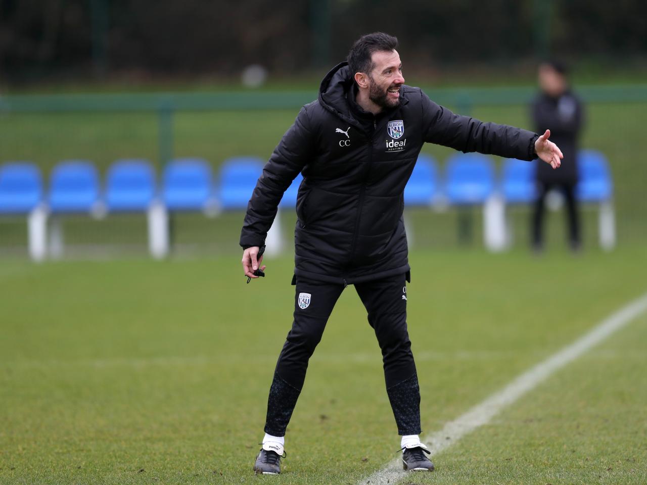 Carlos Corberán wearing a black coat while delivering instructions 