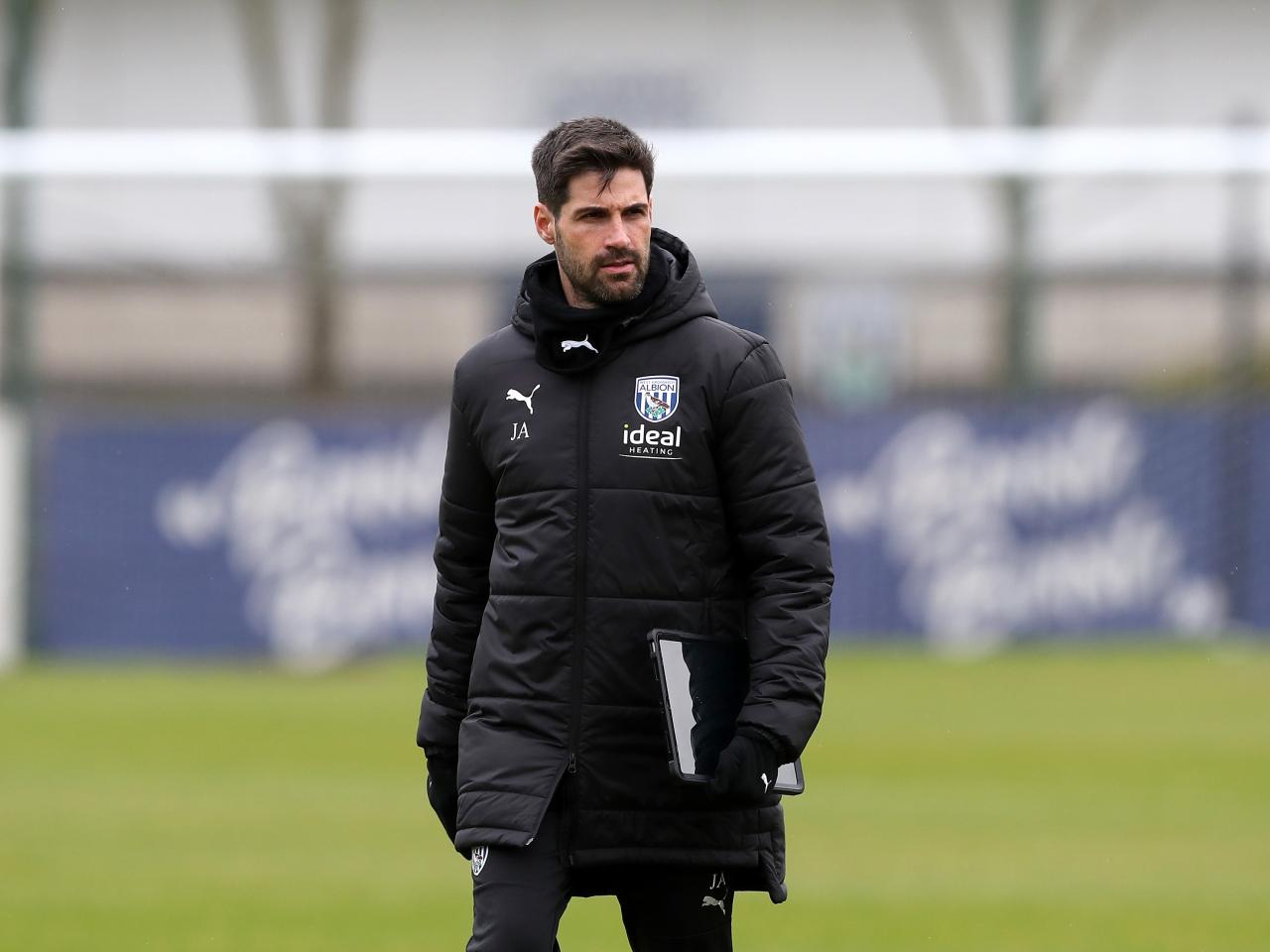 Jorge Alarcon wearing a black coat holding a notepad out on the training pitch