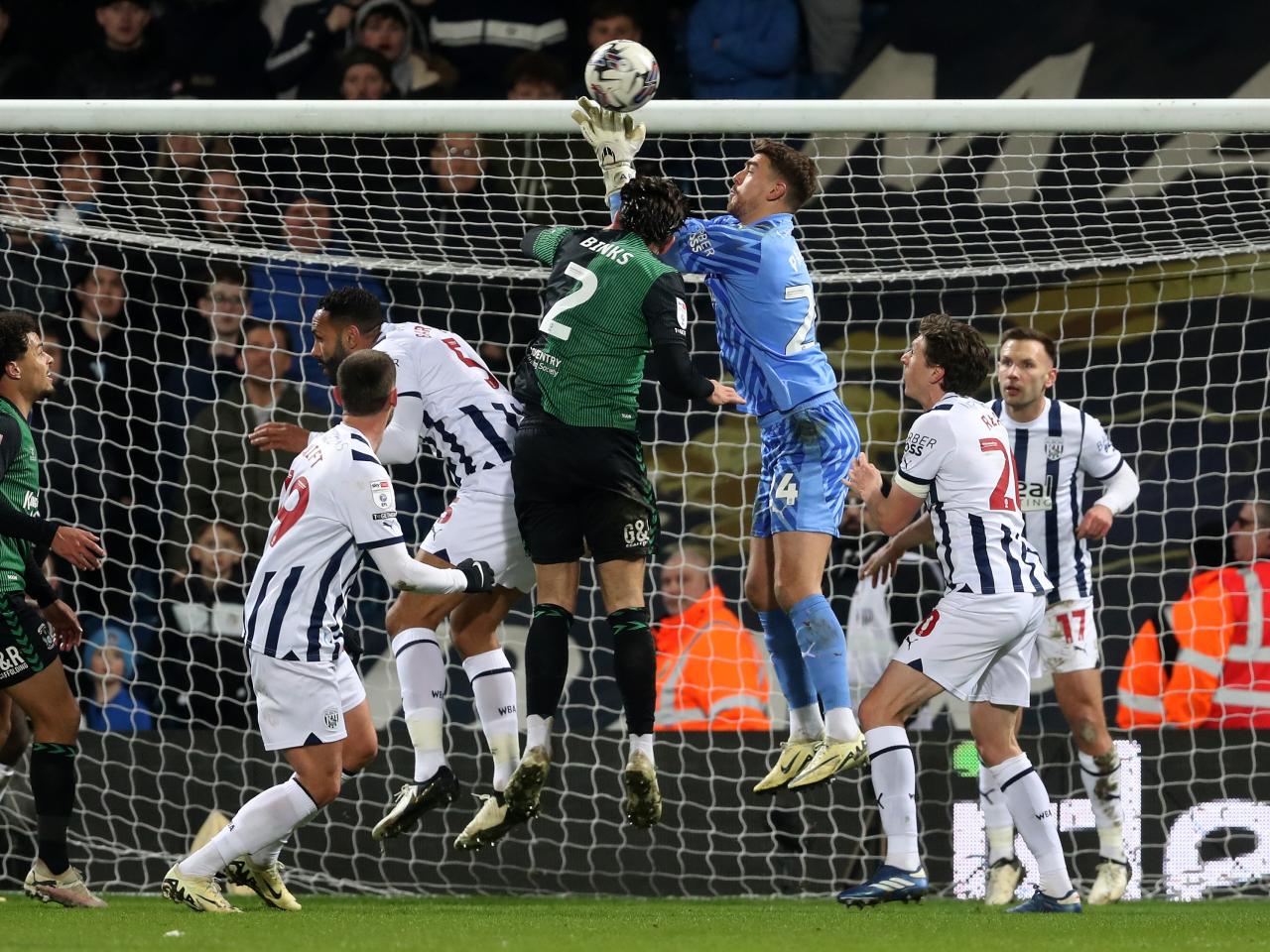 Alex Palmer jumping for the ball in the air under pressure by a Coventry player 