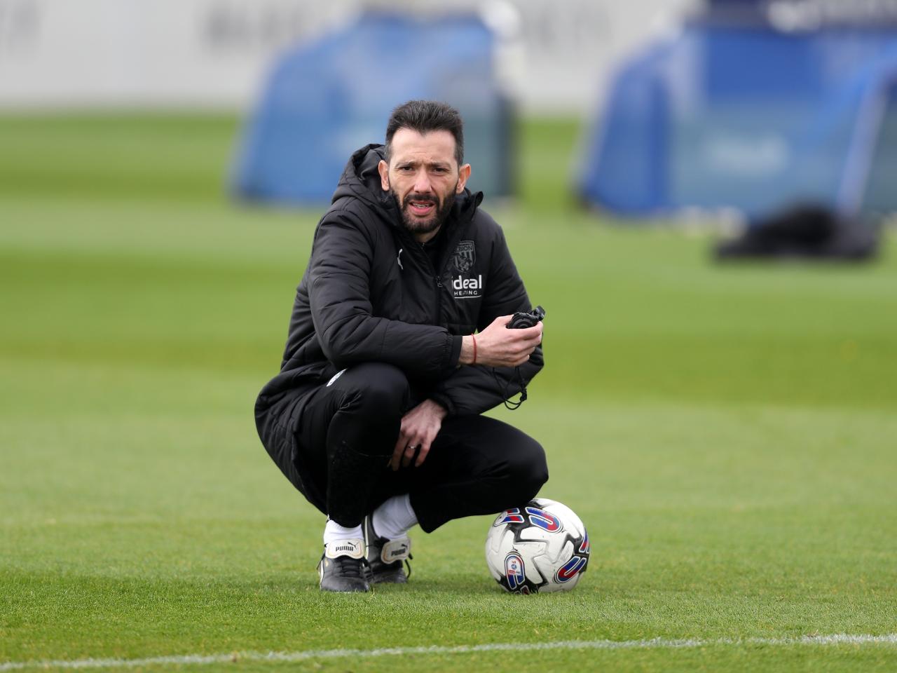 Carlos Corberán crouched down during a training session