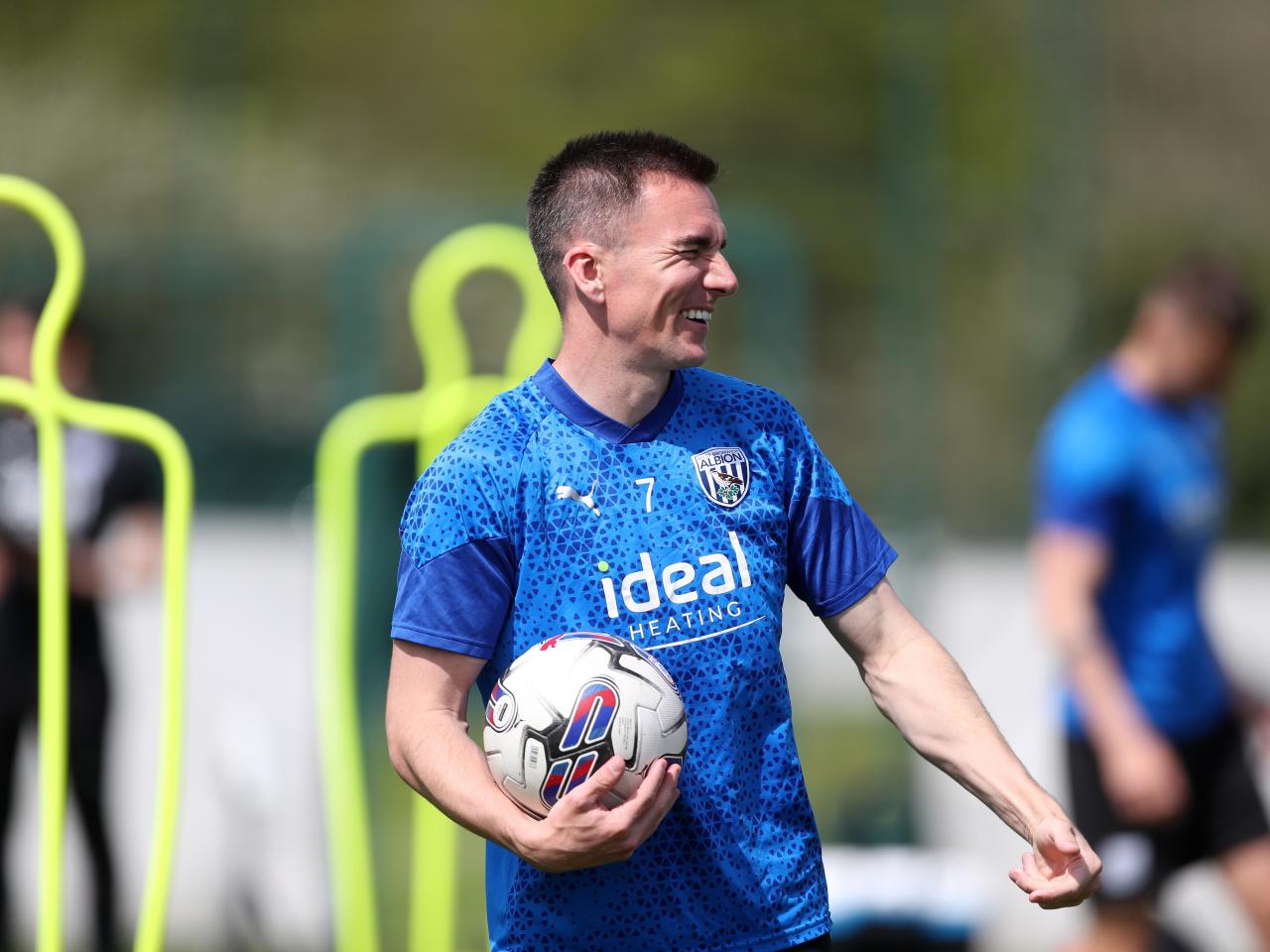 Jed Wallace smiling while holding a ball in training 