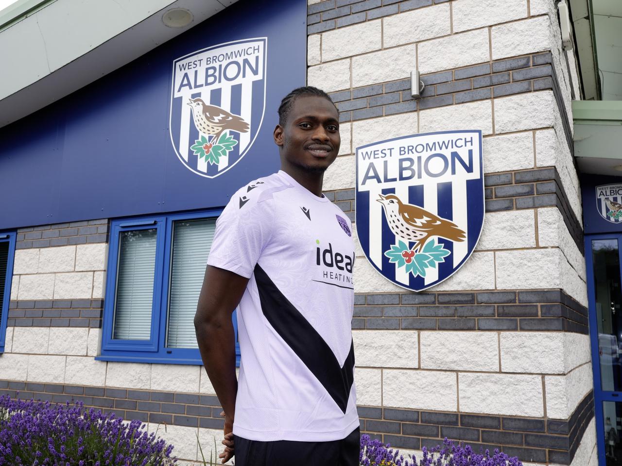 Ousmane Diakité smiling at the camera while stood outside the training ground entrance 