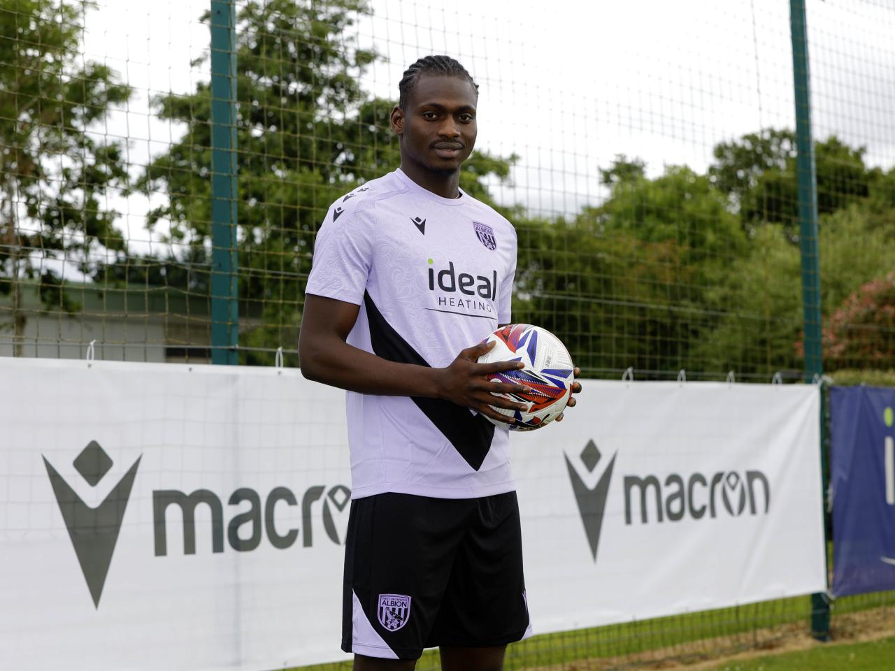 Ousmane Diakité smiling at the camera while holding a ball