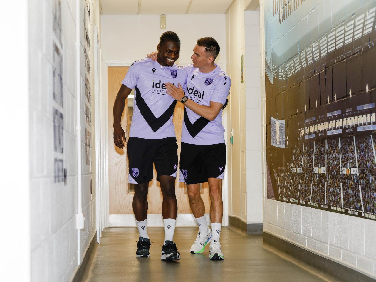 Ousmane Diakité and Jed Wallace laughing while walking down a corridor 