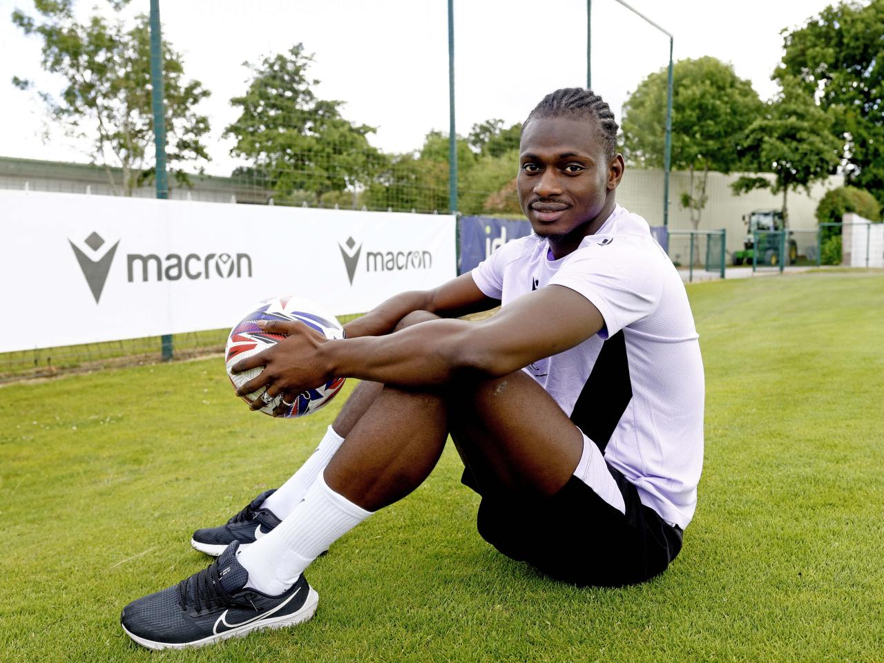 Ousmane Diakité smiling at the camera while sat outside holding a ball
