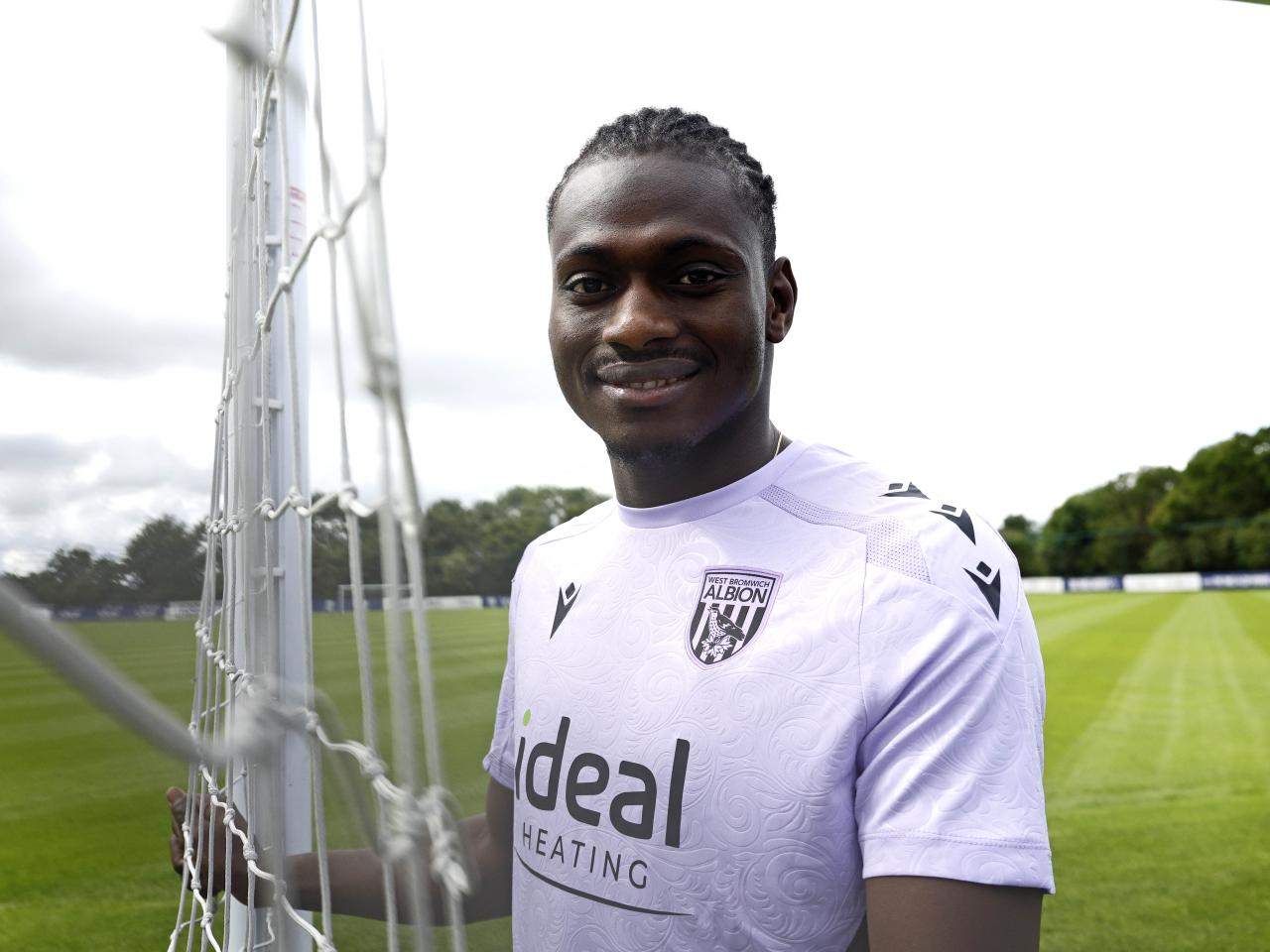 Ousmane Diakité smiling at the camera while stood outside 