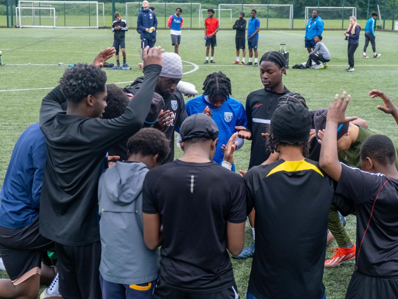 Non bibs team in a pray circle.