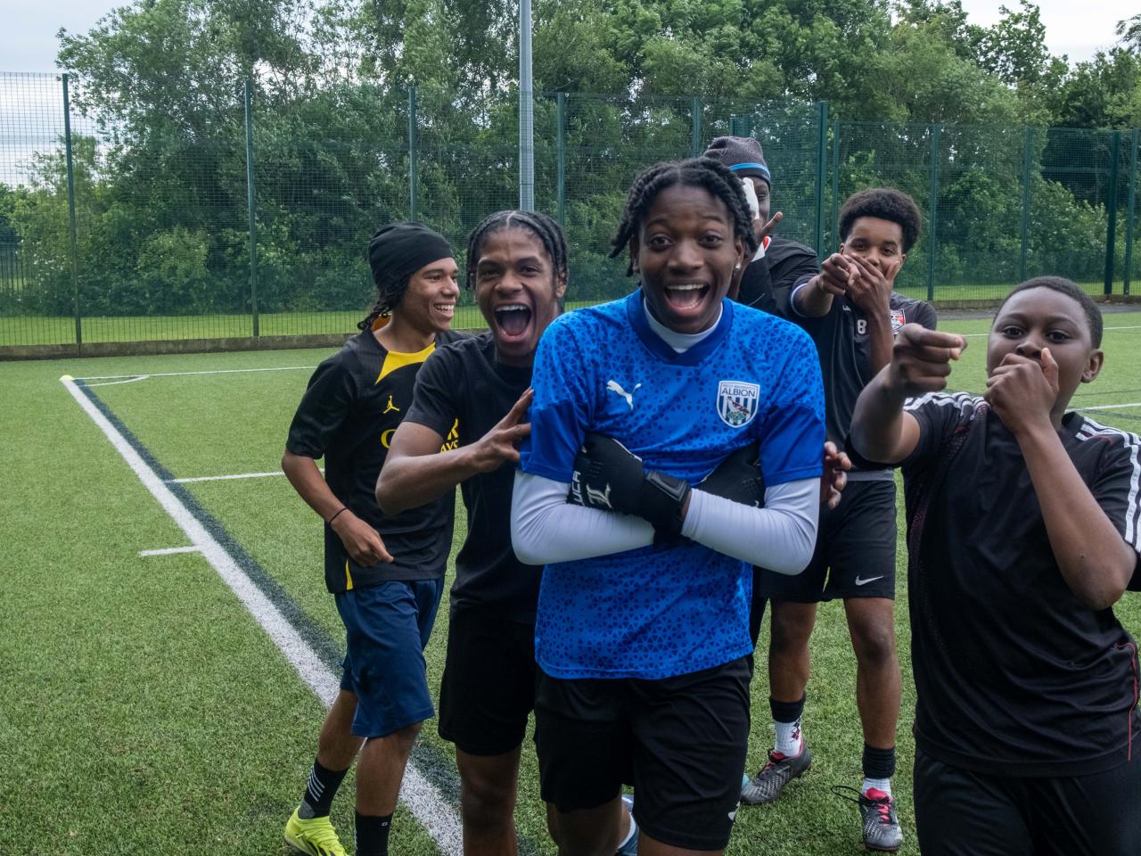 Non bib team celebrate a goal, with players doing various celebrations.