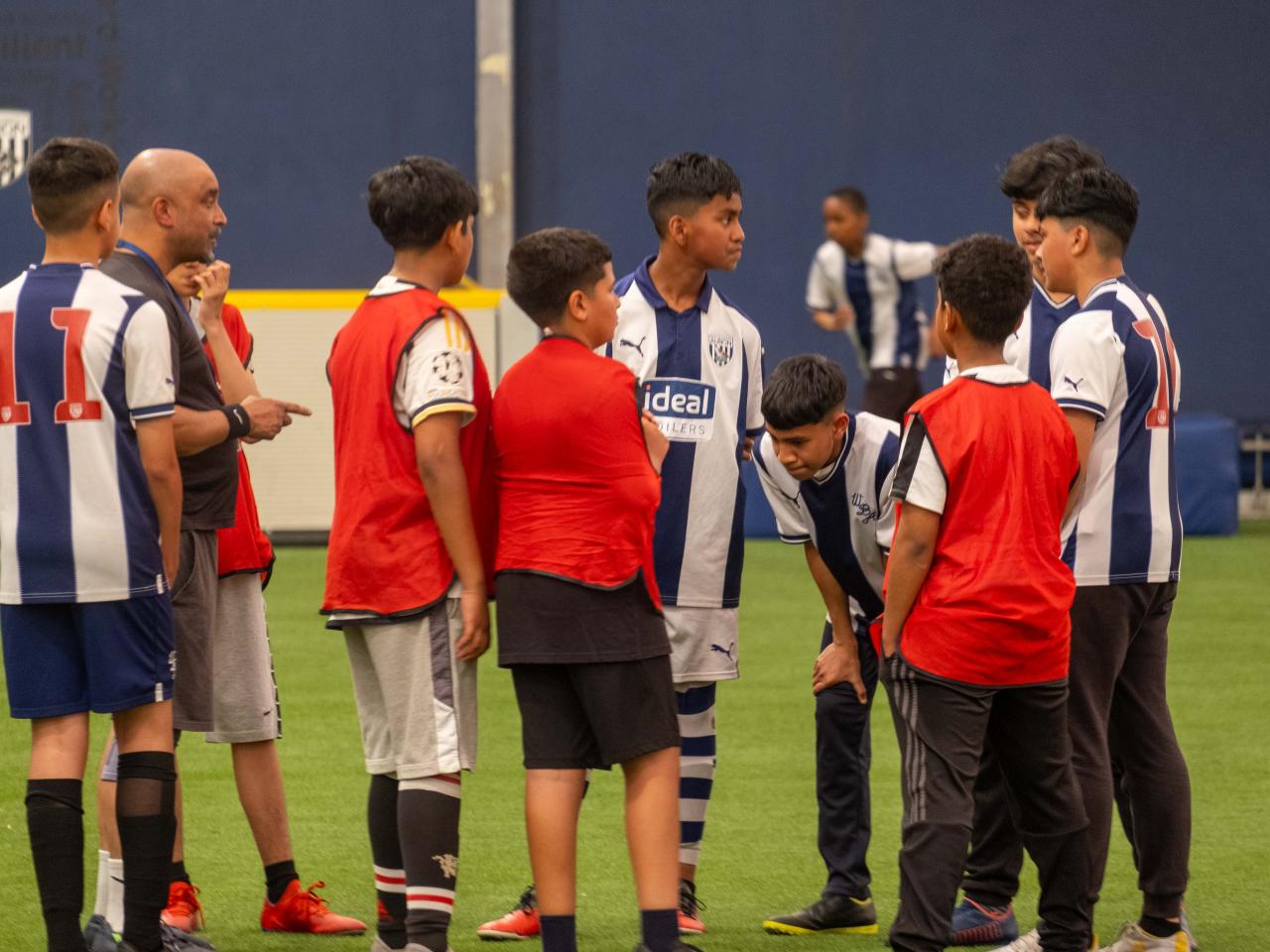 A group of players mainly decked in West Brom home shirts talk during the South Asian Emerging Talent Festival in the Academy Dome.