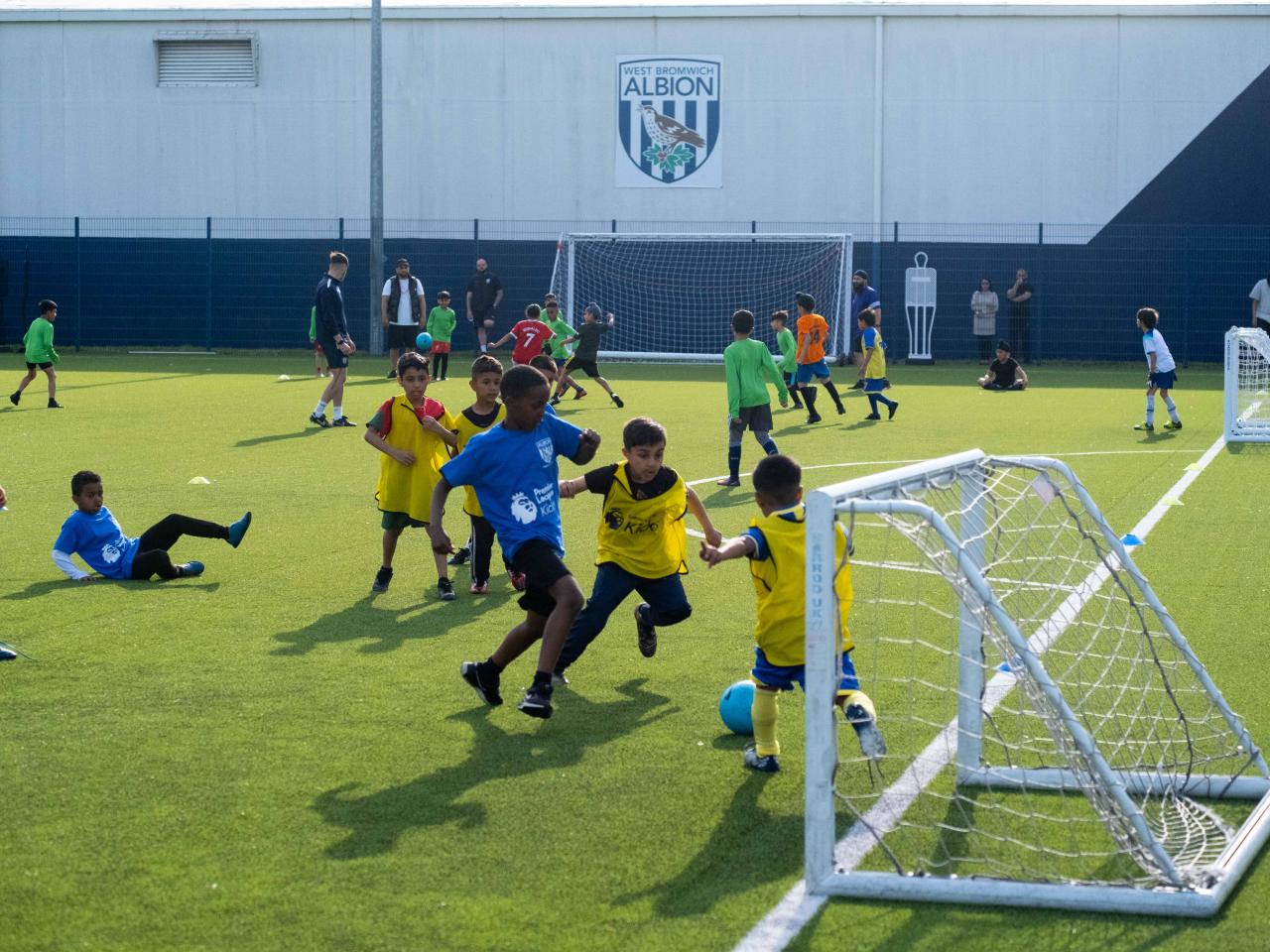 Players wearing yellow bibs try to stop a player in a blue bib from scoring during our South Asian Emerging Talent Festival on the Academy pitch.