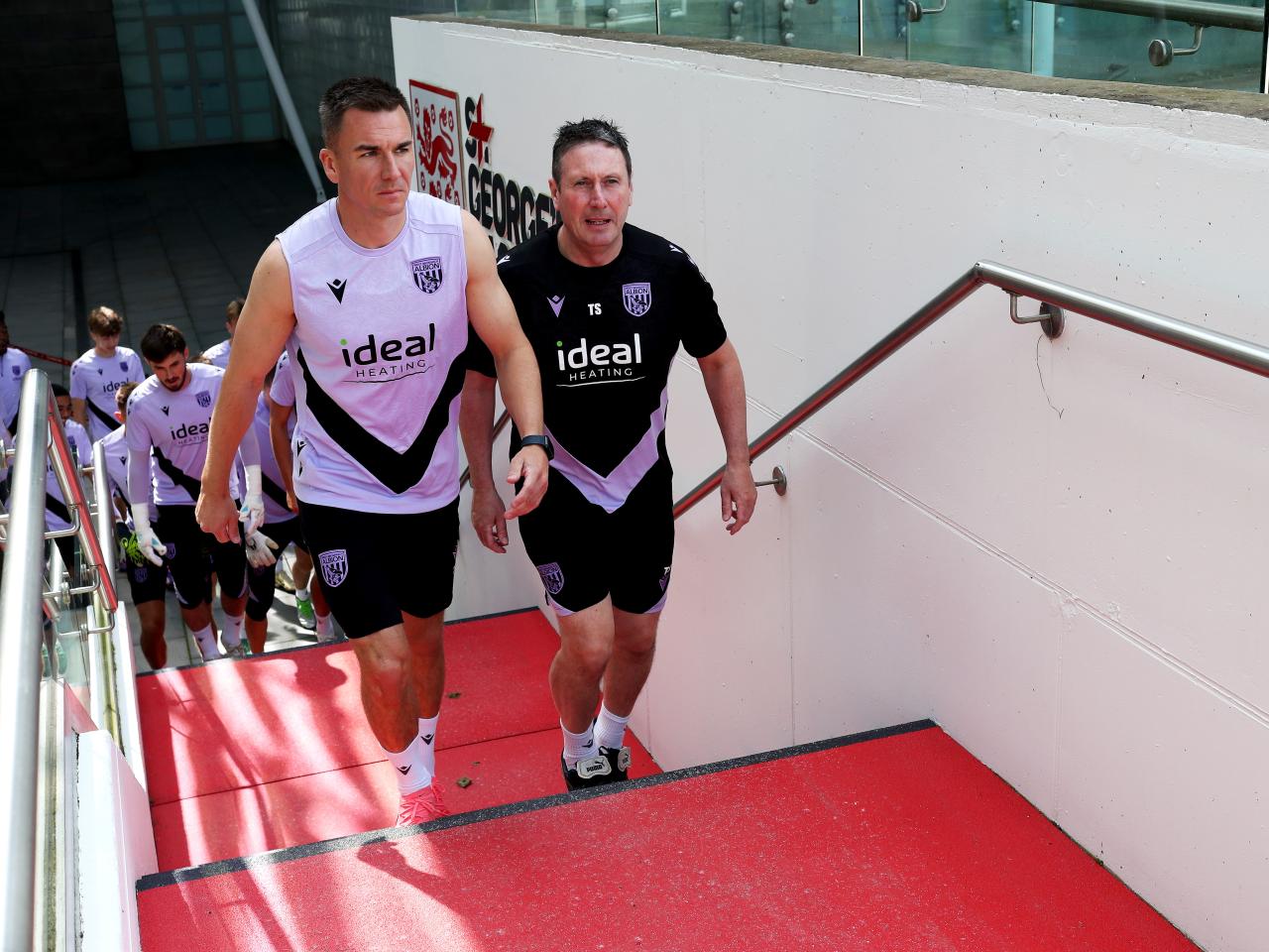 Jed Wallace and Director of Medical Tony Strudwick walking up the steps to the training pitch at St. George's Park