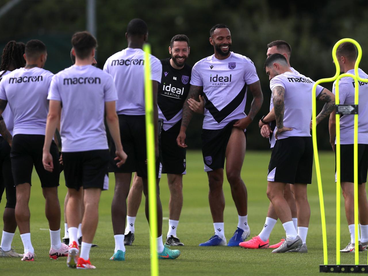 Several players smiling during a break in training with coach Damia Abella 