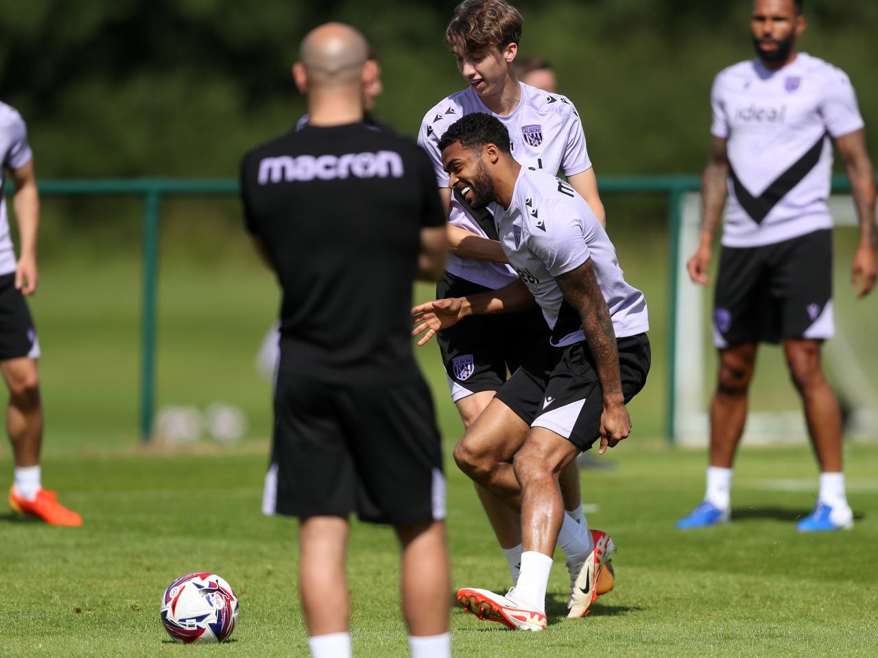 Darnell Furlong and Harry Whitwell smiling while battling for the ball during training 