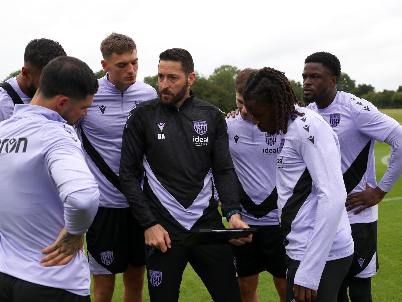 Coach Damia Abella delivering info to several players during a stoppage in the training session