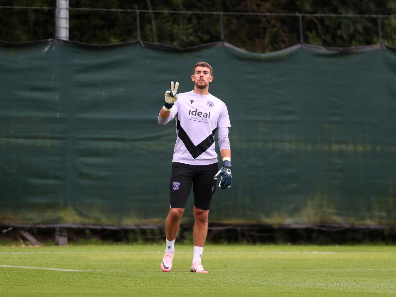 Alex Palmer holding two fingers forwards facing up towards the camera 