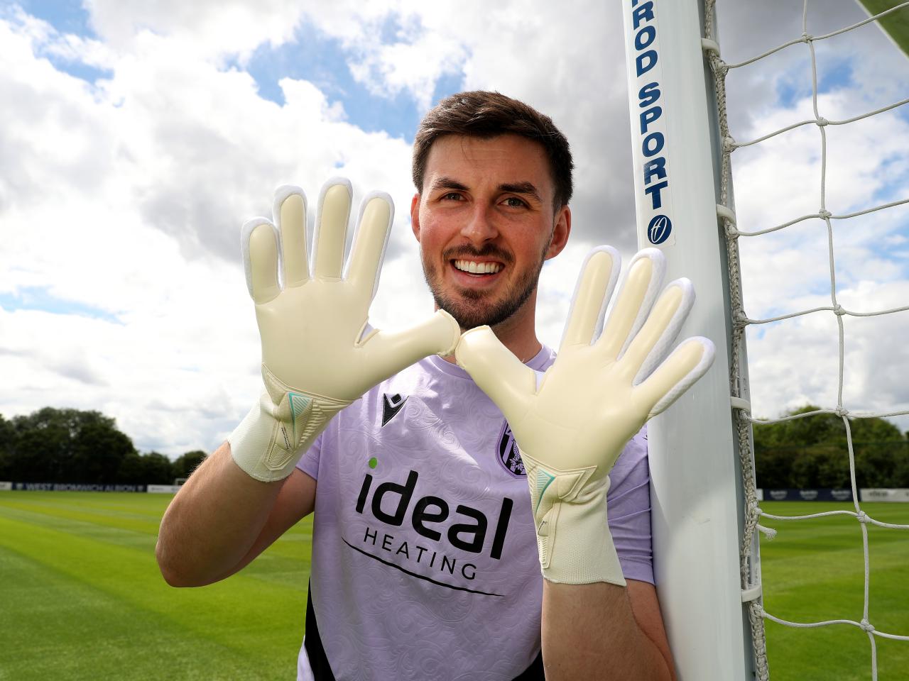 Joe Wildsmith smiling at the camera while holding his gloves up