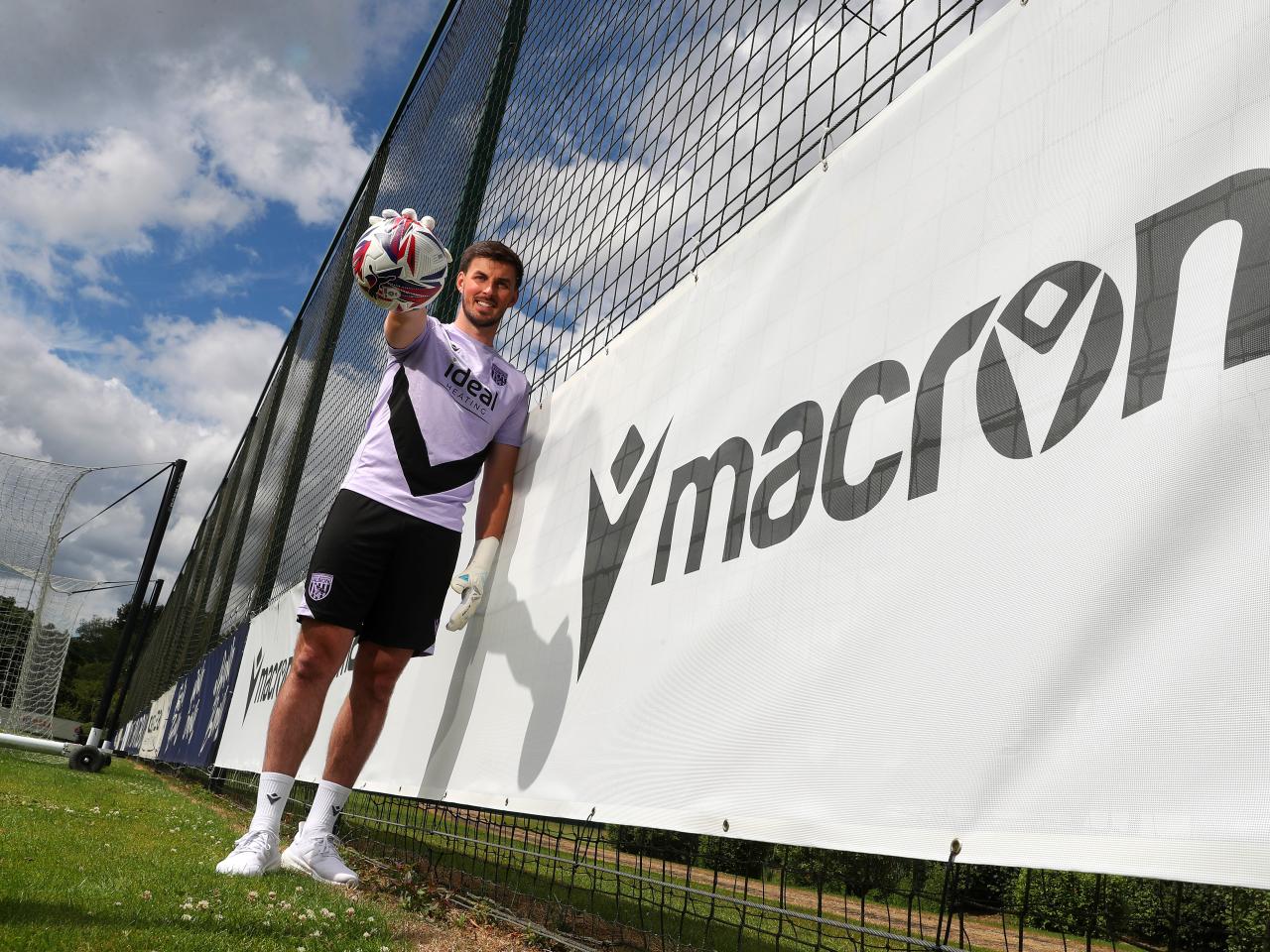 Joe Wildsmith smiling at the camera while holding a football