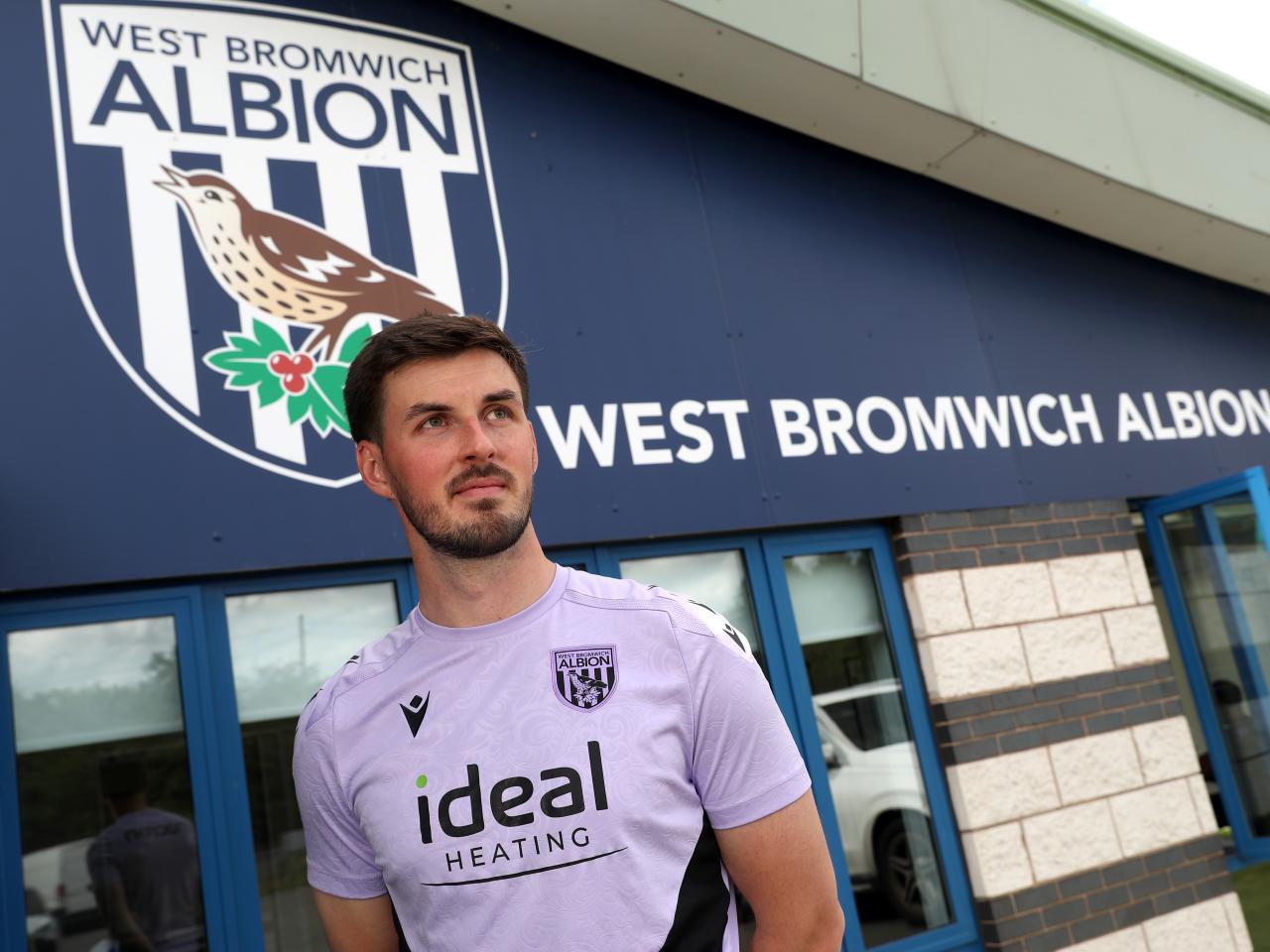 Joe Wildsmith stood in front of Albion branding at the training ground 