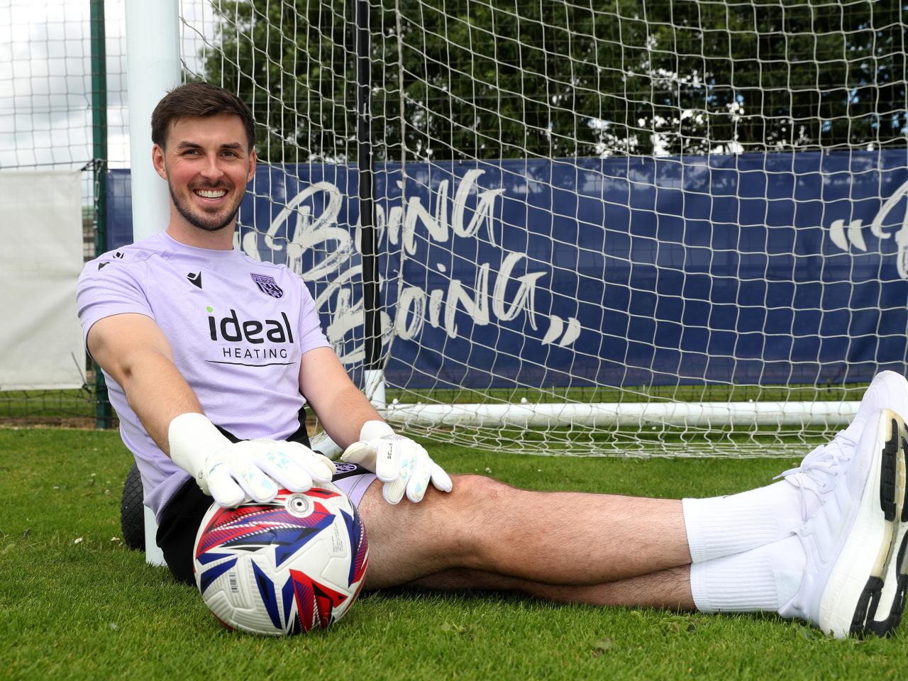 Joe Wildsmith sat on the pitch with the ball by his foot