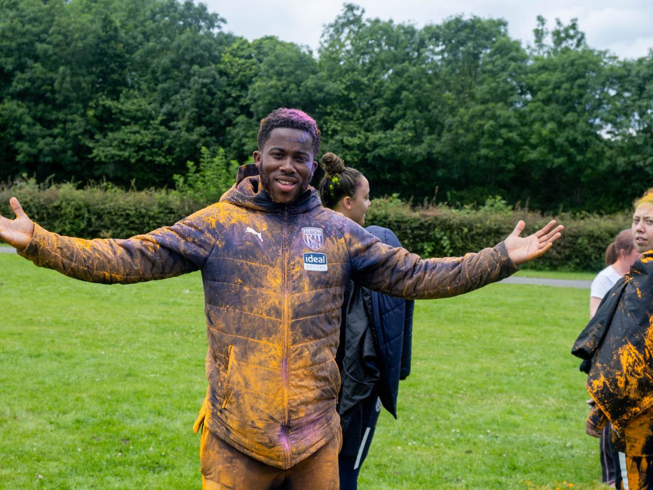 Foundation staff, with arms out, covered in paint.