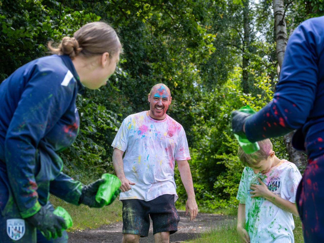 Father & Son running towards Foundation staff at a colour station, throwing paint powder.