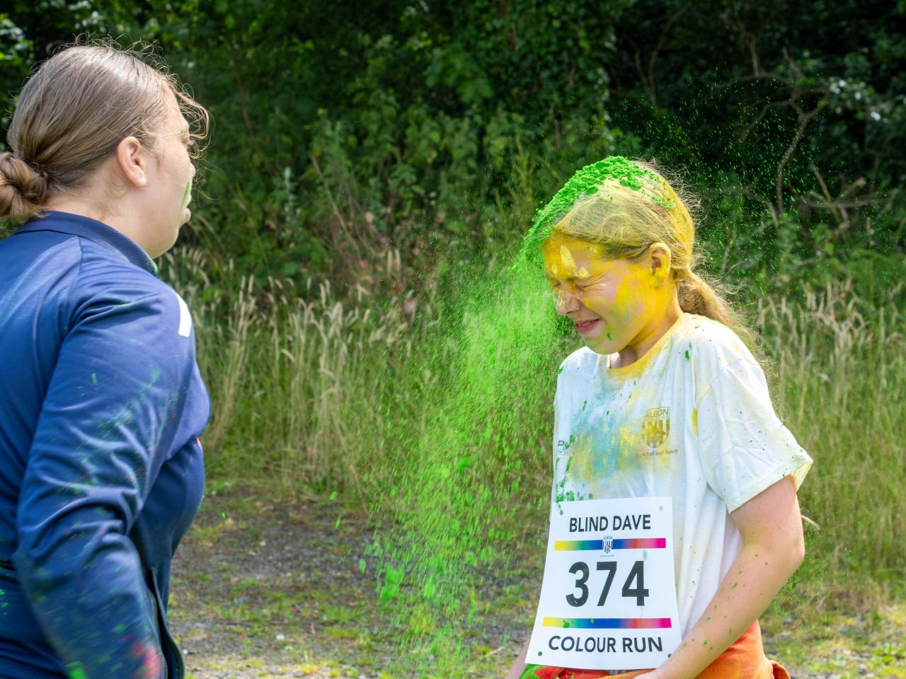 Young participant with a burst of green paint powders falling off of her hair.