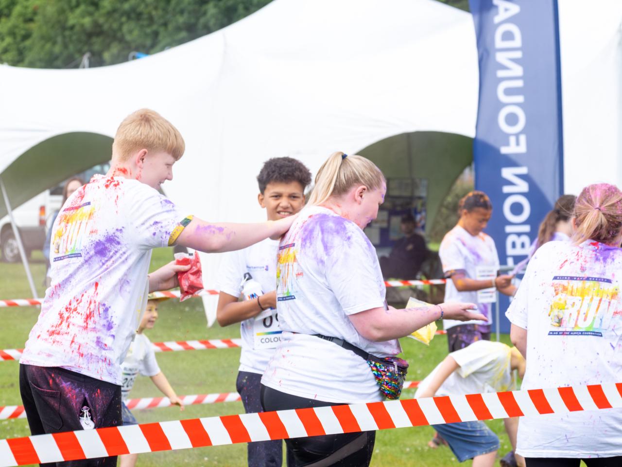 Group of participants inside barrier throwing paint powder.