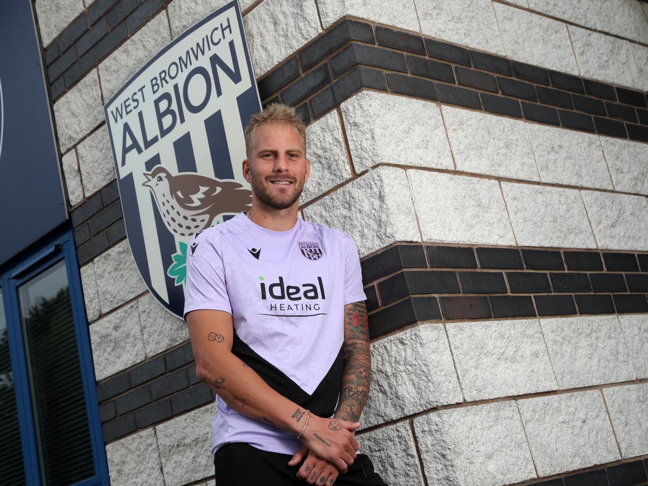 Uroš Račić smiling at the camera while stood outside the front of the training ground 