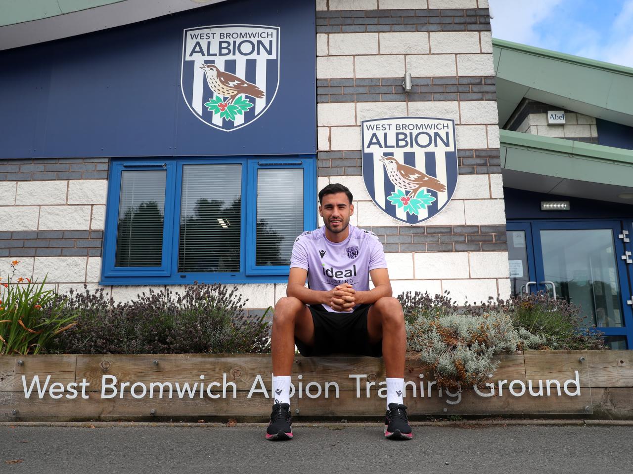 Gianluca Frabotta smiling at the camera while sat outside the front of the training ground 
