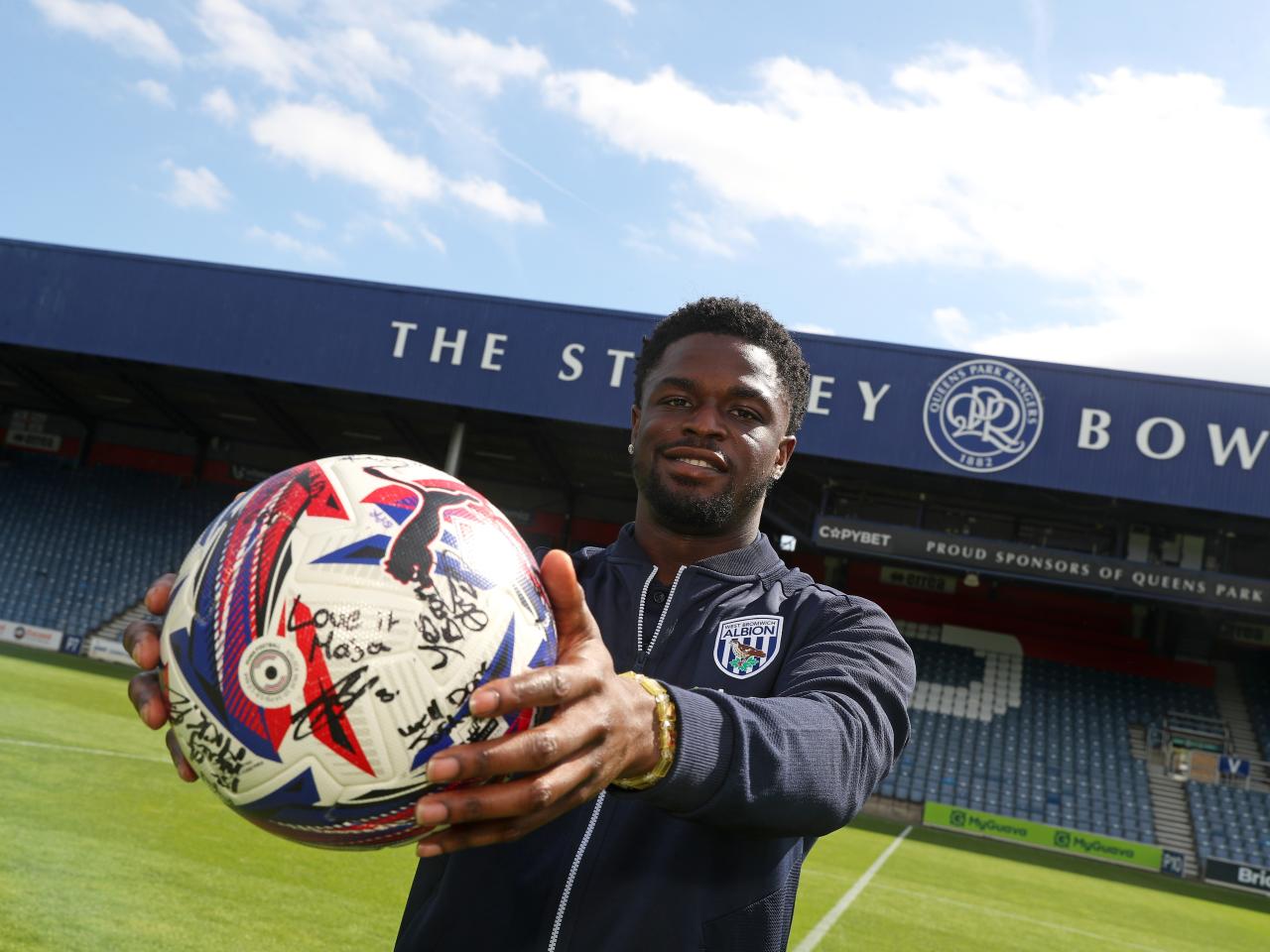 Josh Maja smiling at the camera while holding the match ball at QPR 