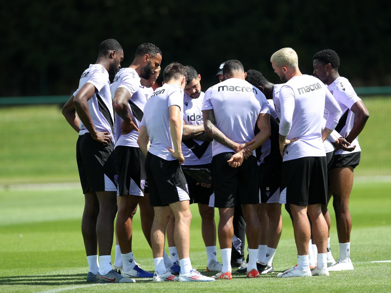 Several players gather in a huddle on the training pitch 