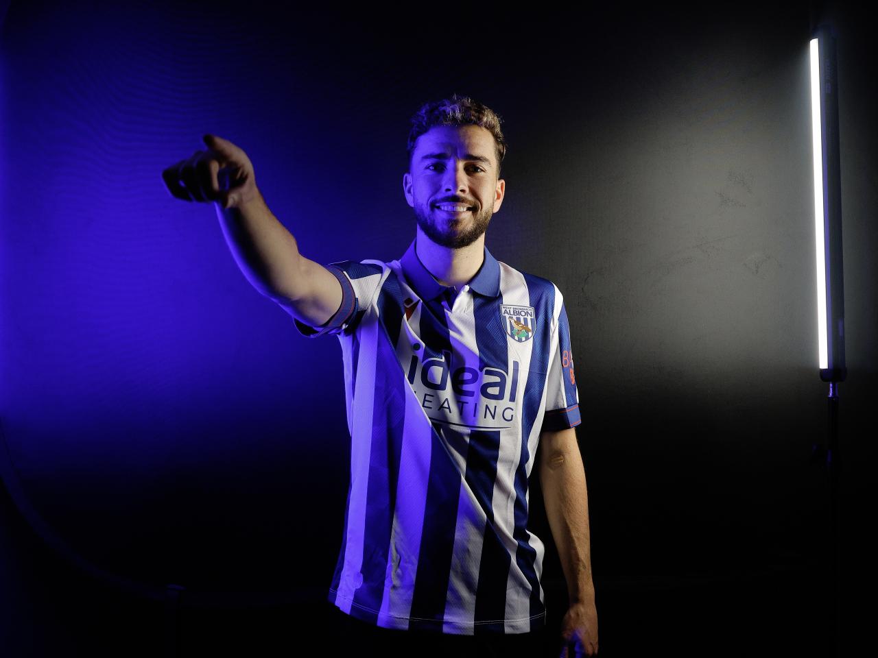Mikey Johnston pointing at the camera while wearing a home shirt and stood in a TV studio 