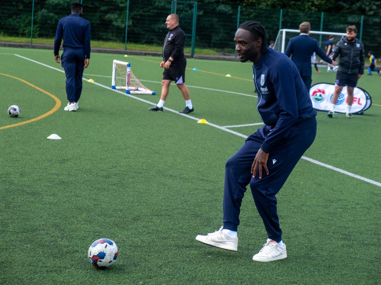 Devante Cole plays football with camp participants.