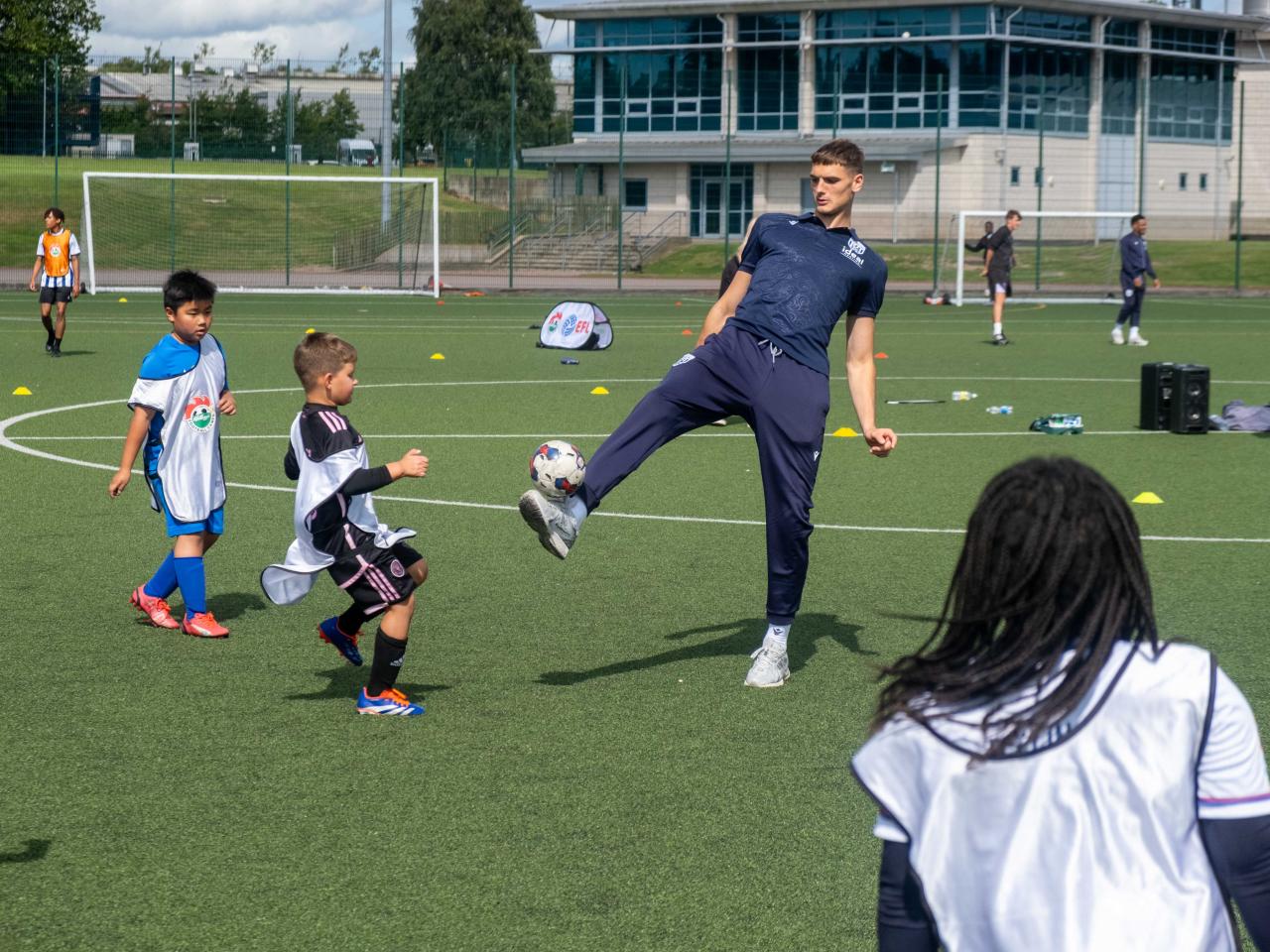 Caleb Taylor plays football with camp participants.