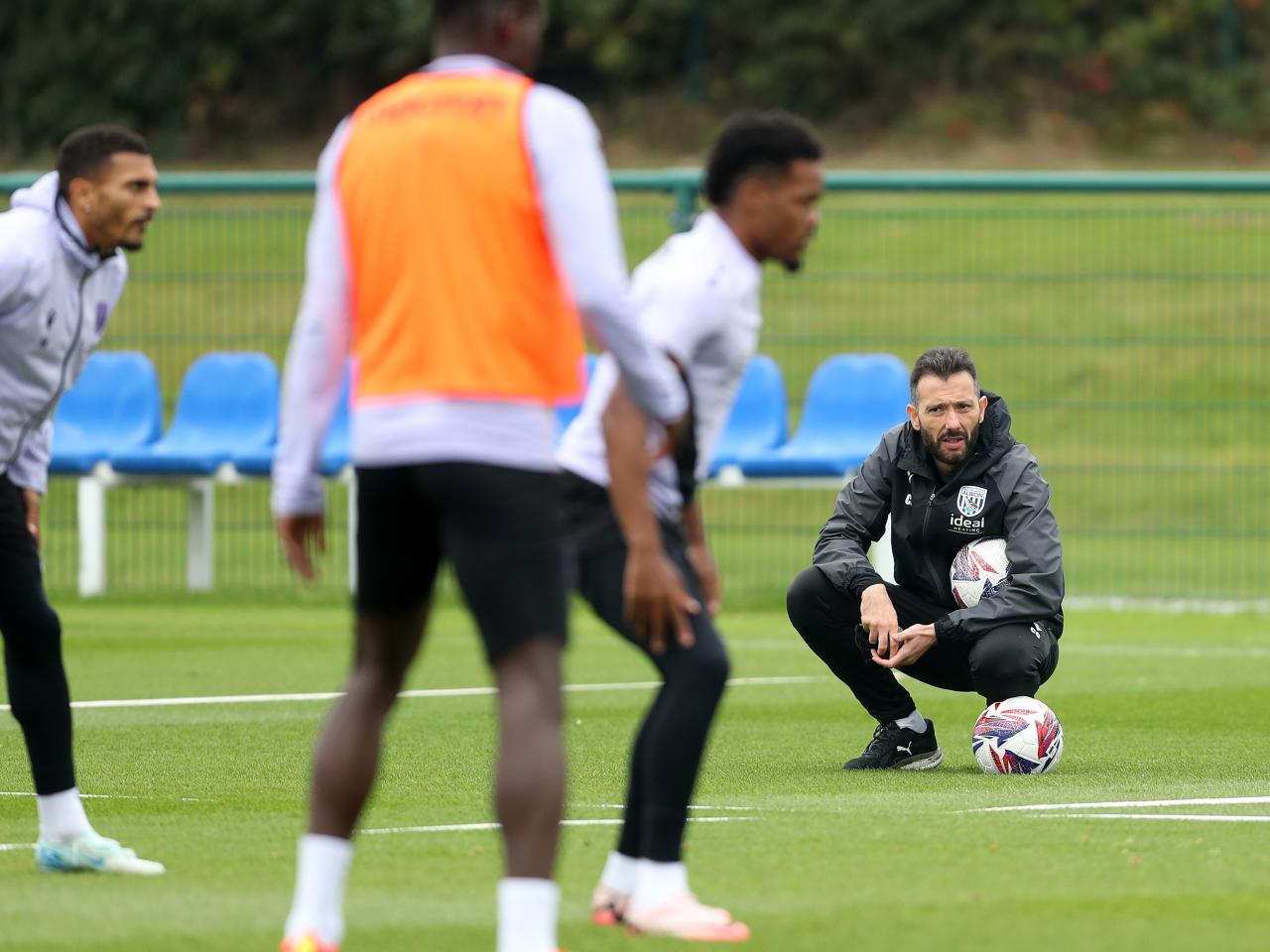 Carlos Corberán crouched down watching a training session 