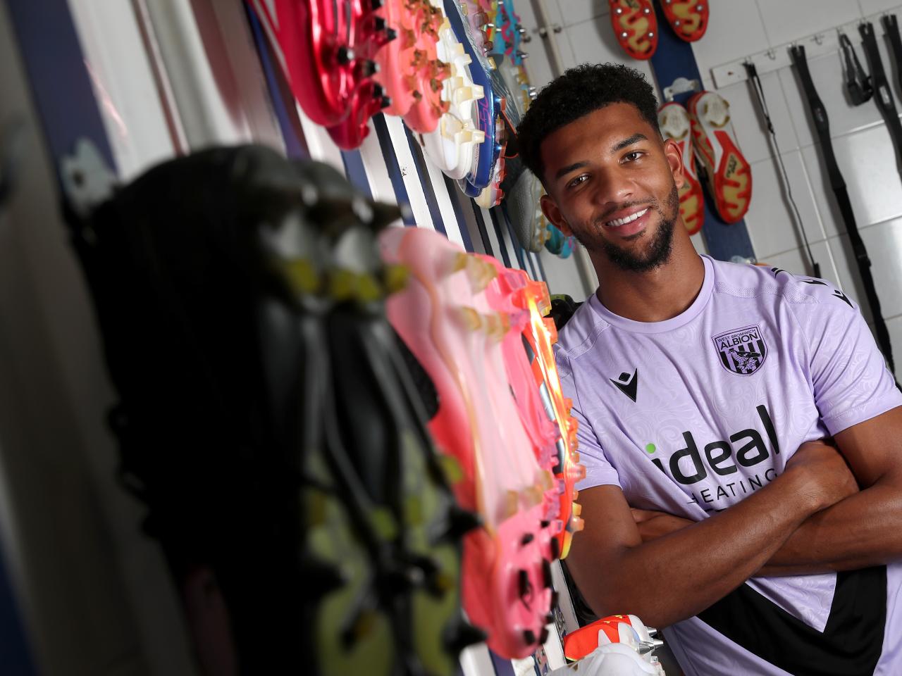 Mason Holgate smiling at the camera with his arms folded while stood in the boot room