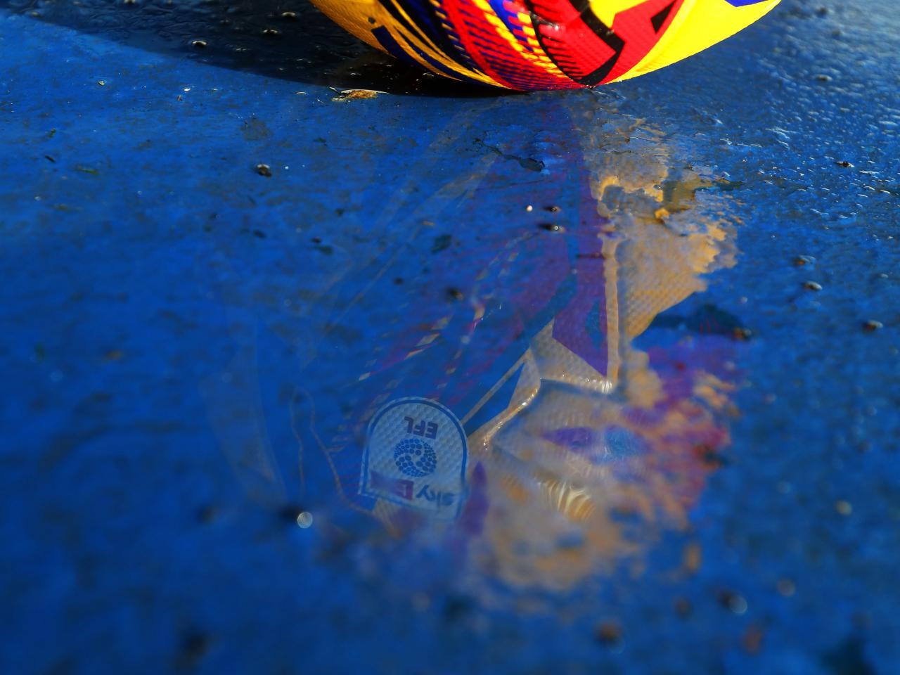 The reflection of a yellow EFL football in a puddle on the side of the pitch at The Hawthorns 