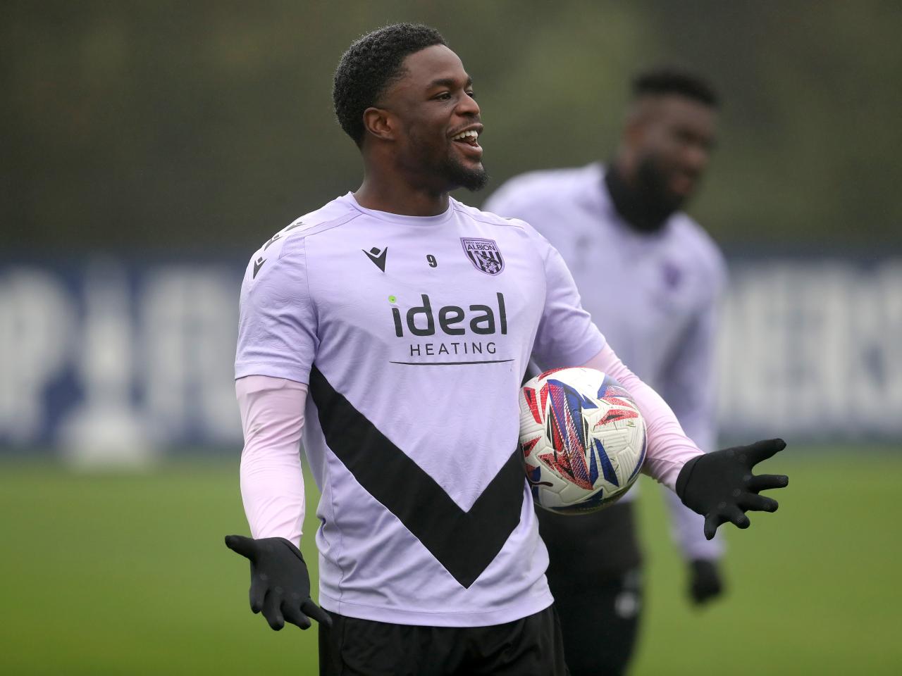 Josh Maja laughing during a training session holding his arms out with a ball 