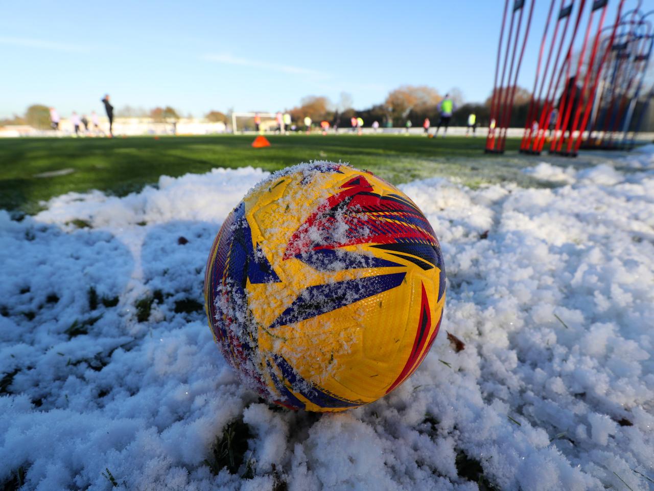 An image of a football covered in snow on the training pitch