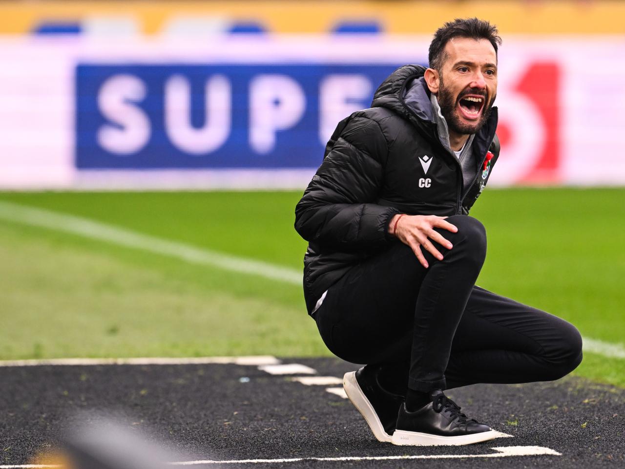 Carlos Corberán crouched down giving instructions to his players at Hull City