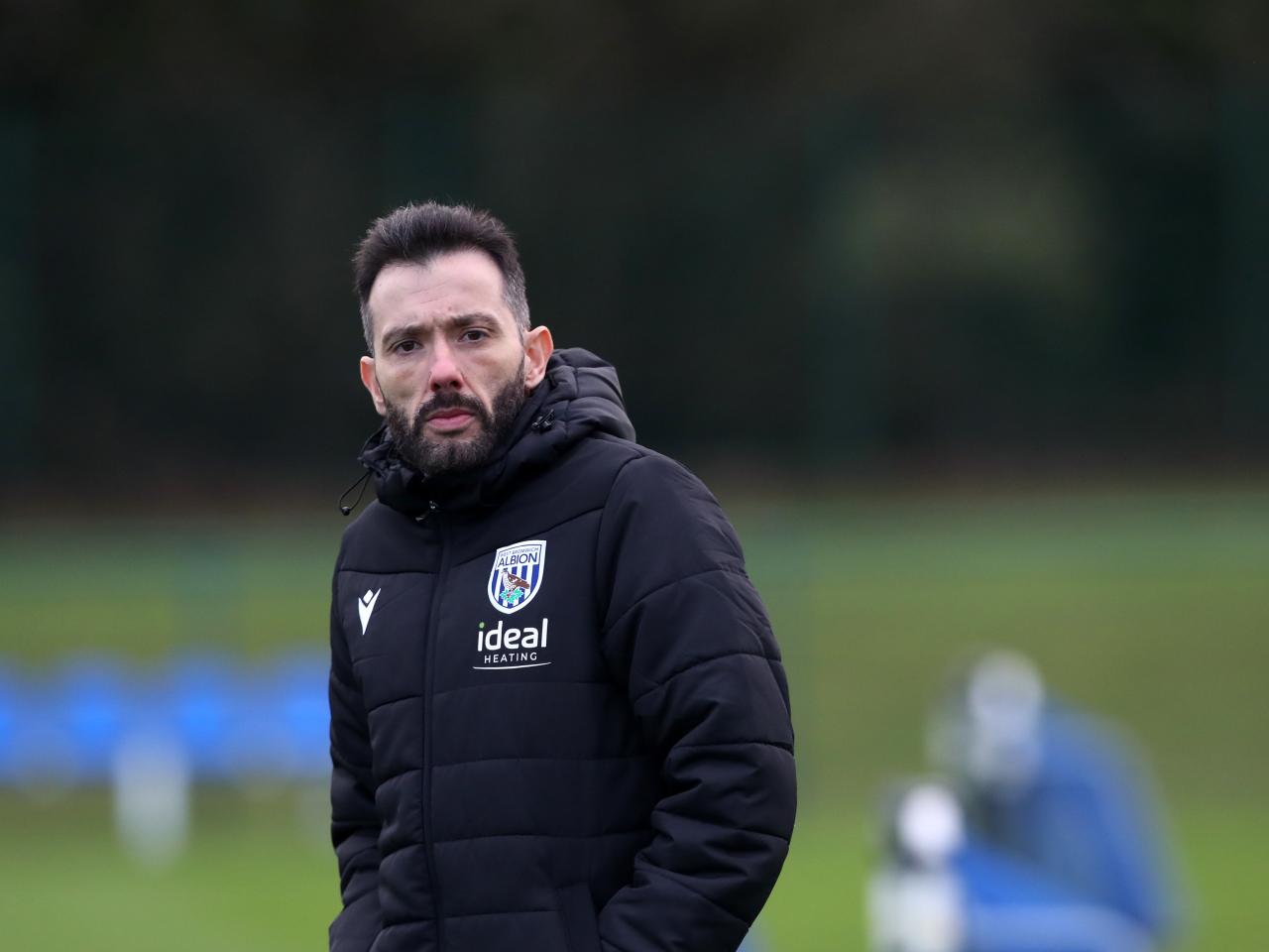 Carlos Corberán in a coat watching training 