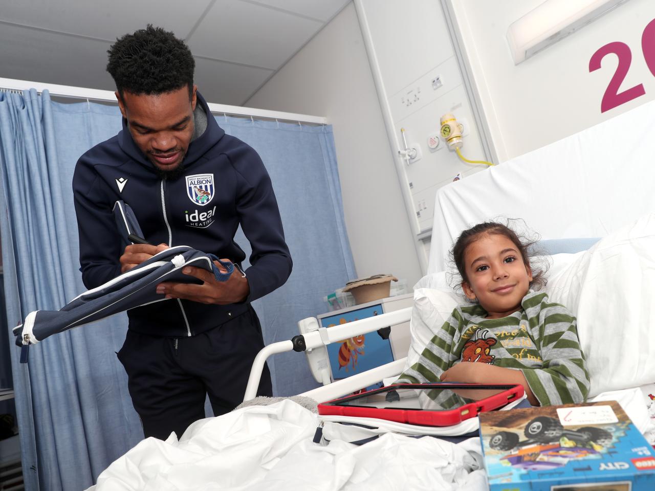 Grady Diangana signs an object for a young patient at Midlands Metropolitan University Hospital 