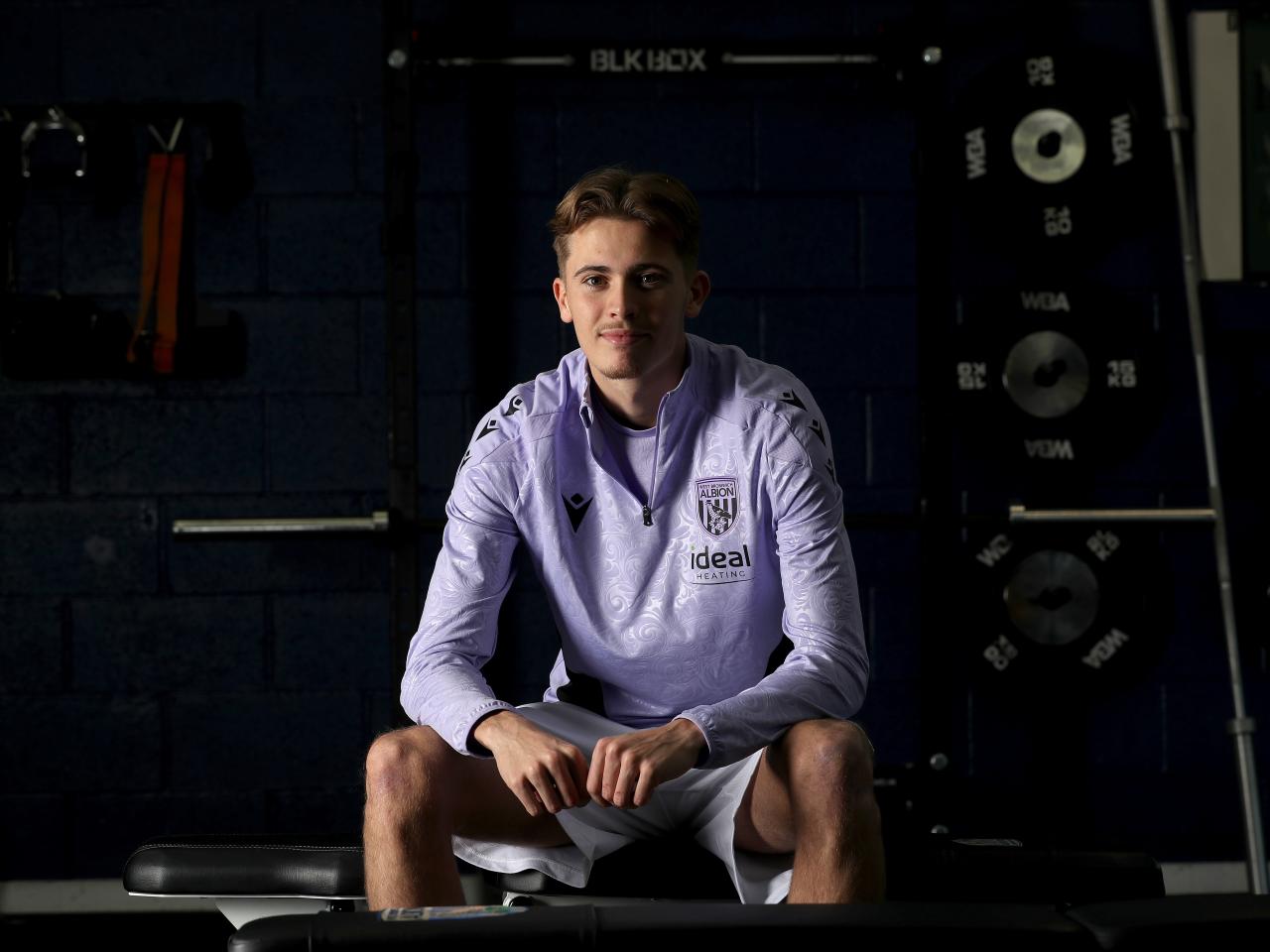 Isaac Price sat down in training gear smiling at the camera 